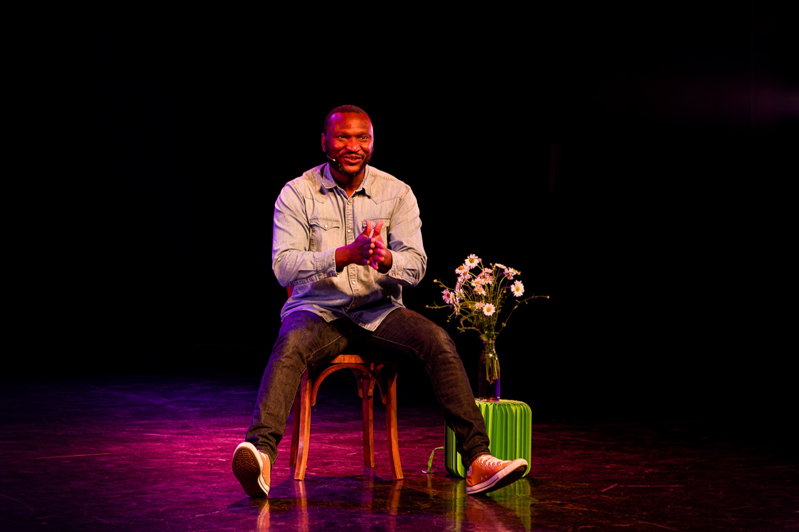 Nilson souriant, assis sur scène près de fleurs en 2026